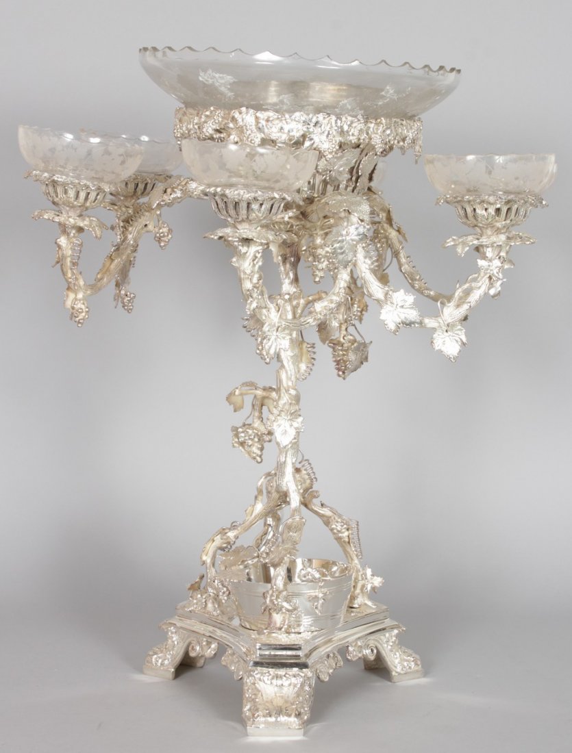 AN IMPRESSIVE SILVER PLATED CENTREPIECE,: AN IMPRESSIVE SILVER PLATED CENTREPIECE, naturalistically cast with grape and vine decoration, with a central bowl and three pairs of scrolling branches, all with cut glass inserts. 2ft 0ins high.