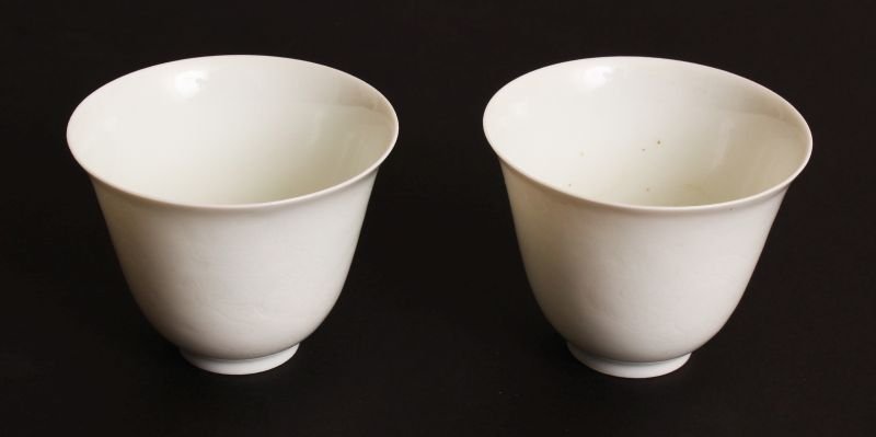 A PAIR OF CHINESE MING STYLE WHITE GLAZED PORCELAIN: A PAIR OF CHINESE MING STYLE WHITE GLAZED PORCELAIN WINE CUPS, each faintly incised underneath the glaze with dragons pursuing flaming pearls, each base with a faint six-character Chenghua mark, 2.4in