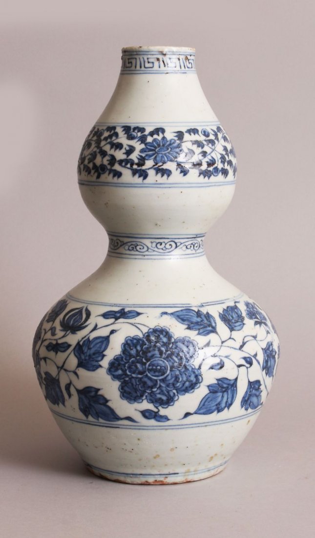 A CHINESE YUAN STYLE BLUE & WHITE DOUBLE GOURD: A CHINESE YUAN STYLE BLUE & WHITE DOUBLE GOURD PORCELAIN VASE, decorated with bands of formal scrolling flowerheads and leafage, the base unglazed, 13.25in high.