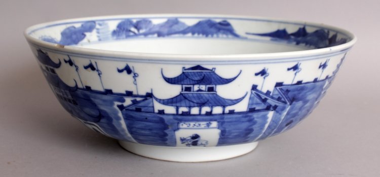 A 19TH CENTURY CHINESE BLUE & WHITE PORCELAIN BOWL, the: A 19TH CENTURY CHINESE BLUE & WHITE PORCELAIN BOWL, the sides painted with a riverside scene of a fortified settlement, the base with a four-character Kangxi mark, 10.1in diameter & 3.6in high.
