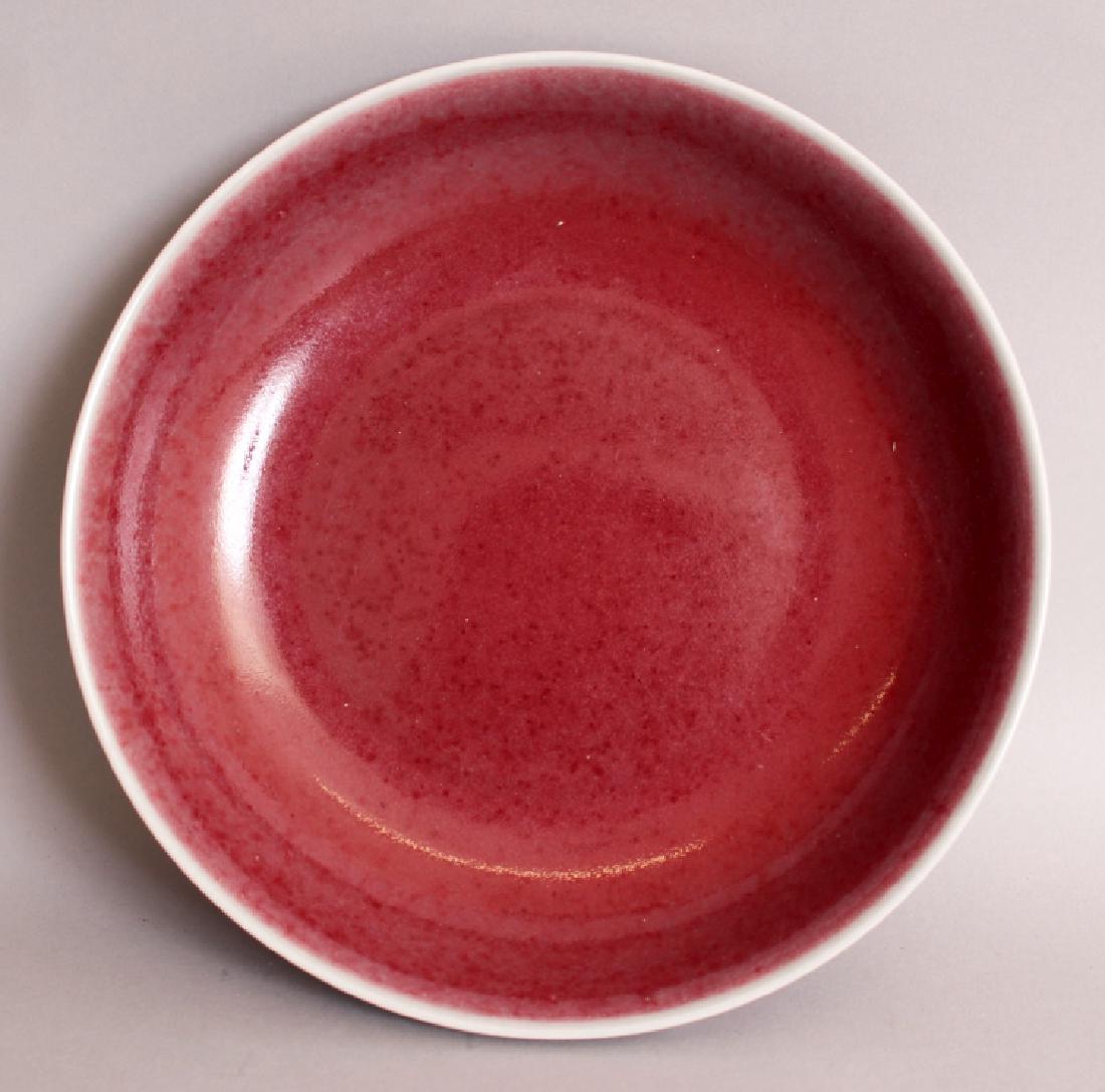 A CHINESE MING STYLE COPPER RED PORCELAIN SAUCER DISH,: A CHINESE MING STYLE COPPER RED PORCELAIN SAUCER DISH, applied with a mottled glaze, the base with a six-character Xuande mark, 8.7in diameter.