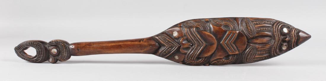 A MAORI CARVED TRIBAL PADDLE with mother-of-pearl: A MAORI CARVED TRIBAL PADDLE with mother-of-pearl inlay. 21ins long.