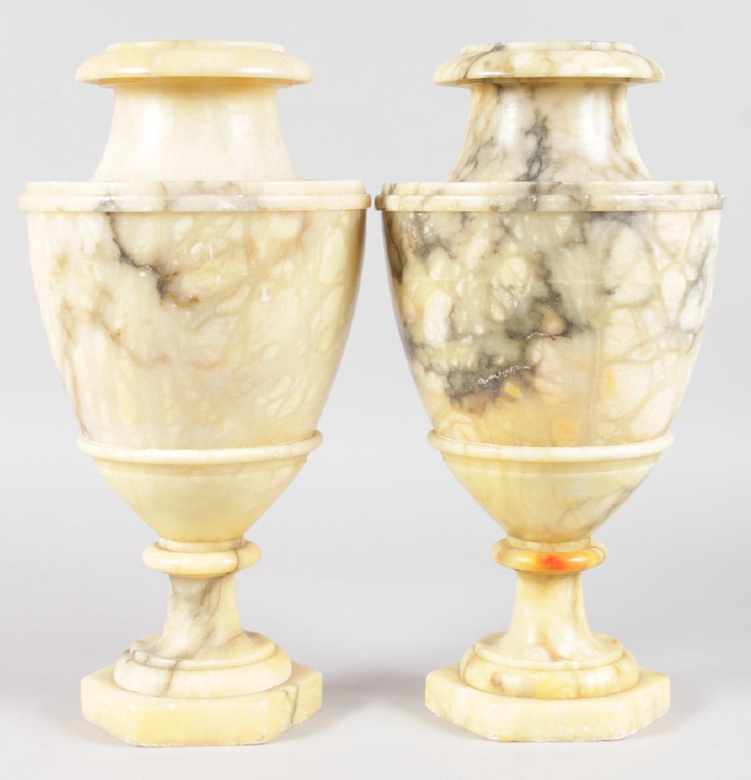 A PAIR OF URN SHAPED ALABASTER VASES on octagonal: A PAIR OF URN SHAPED ALABASTER VASES on octagonal bases. 13ins high.