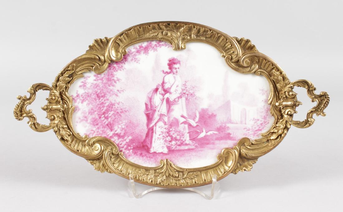 A 19TH CENTURY FRENCH ORMOLU MOUNTED PINK PORCELAIN TWO: A 19TH CENTURY FRENCH ORMOLU MOUNTED PINK PORCELAIN TWO HANDLED TRAY, a young lady in a garden with doves. 13ins long.