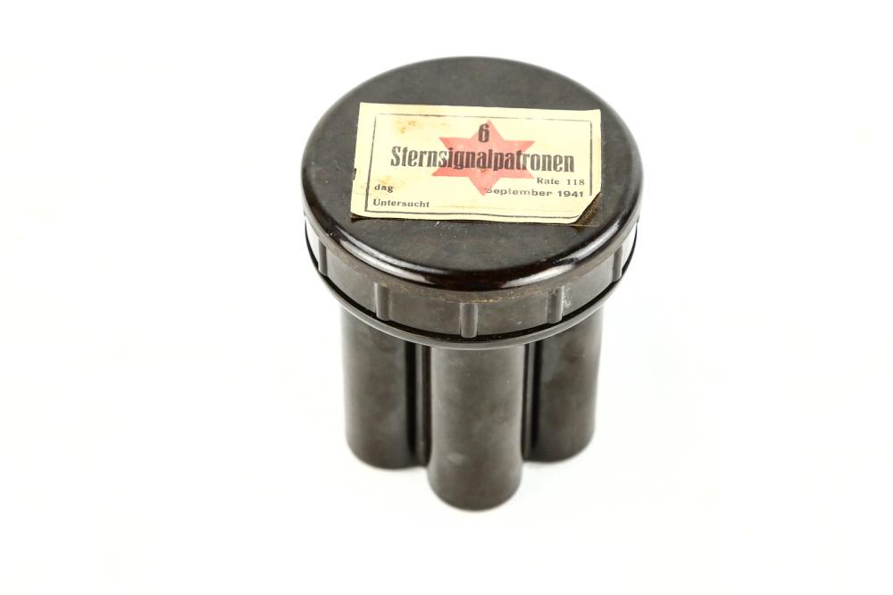WWII German Flare Case: WWII German flare case is a Bakelite case made to hold six flare cartridges for a flare gun, paper label affixed to top reads "6 Sternsignalpatronen," dated September 19, 1941, measures 4" in diameter