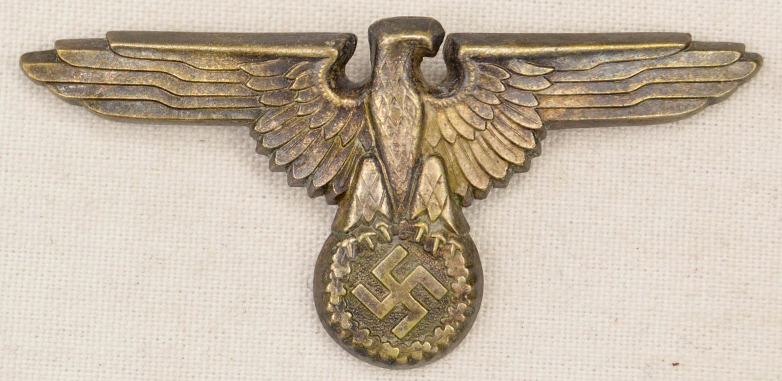 German WWII Waffen SS Officer's Visor Cap Eagle: German World War II Waffen SS Officers Visor Cap Eagle. Measures 2 3/4" wide by 1 1/4" tall. The front shows a Waffen SS eagle clutching a swastika in his talons. The reverse side is maker marked ��