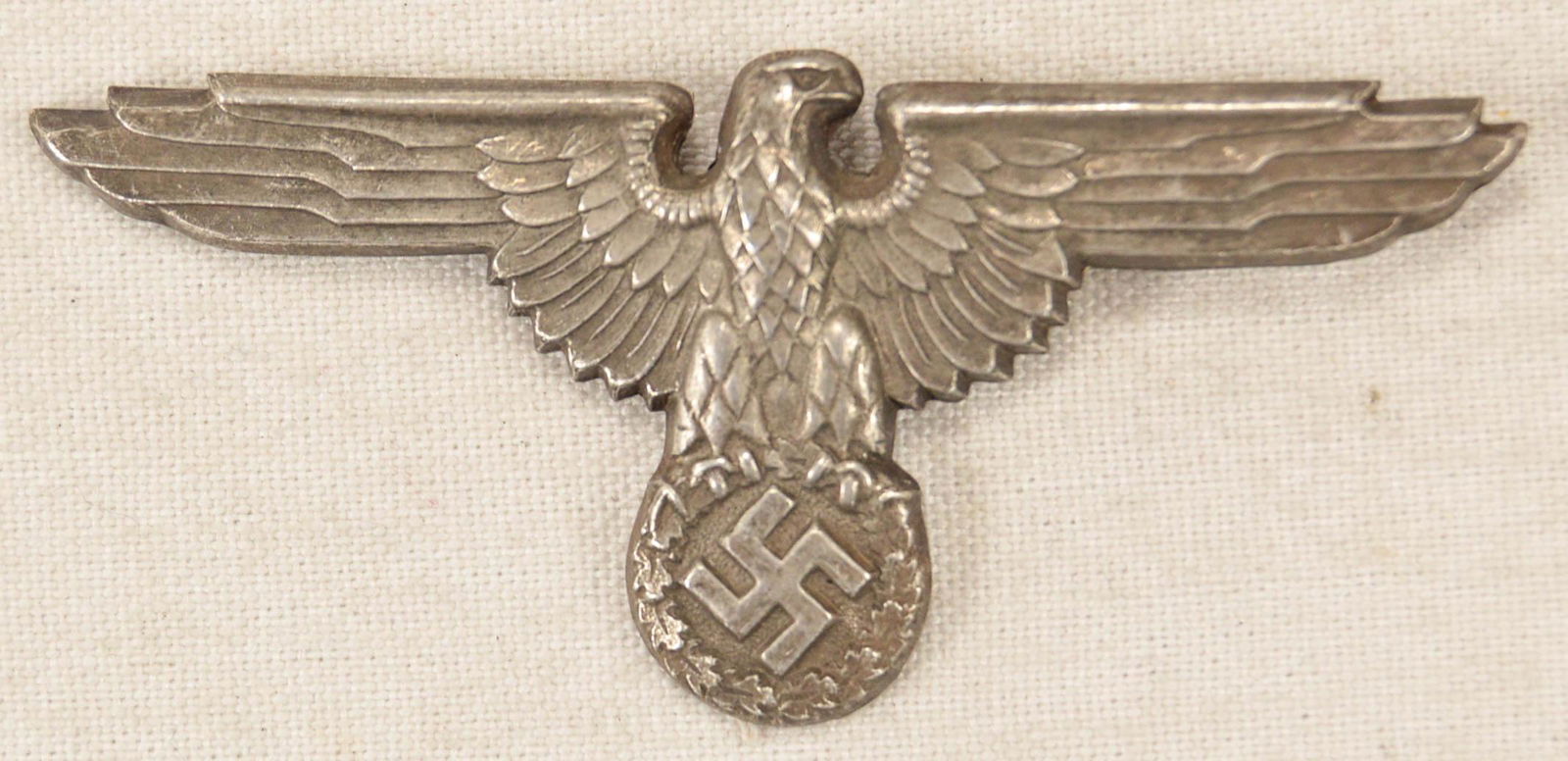 German WWII Waffen SS Officer Visor Cap Eagle: German World War II Waffen SS Officers Visor Cap Eagle. Measures 2 3/4" wide by 1 1/4" tall. The front shows a Waffen SS eagle clutching a swastika in his talons. The reverse side is maker marked ‘R
