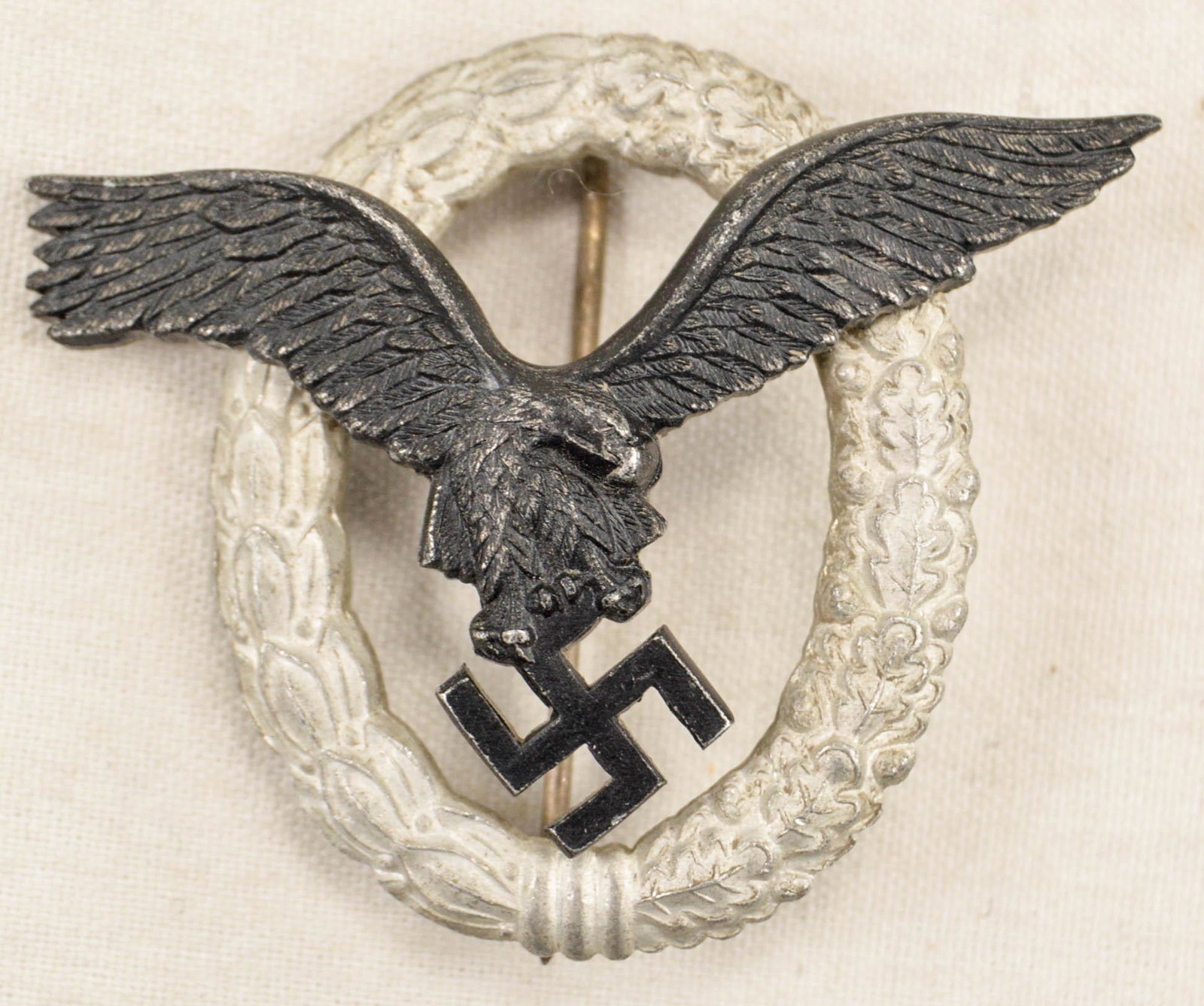 German WWII Luftwaffe Pilot Badge: German World War II Luftwaffe Pilot Badge. The front shows a flying eagle clutching a swastika in his talons. Both are surrounded by an oval oak leaf wreath. The reverse side is maker marked ‘GWL’