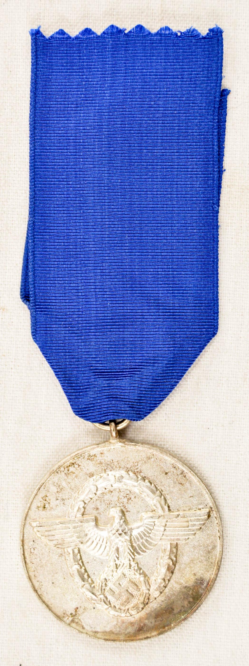 German WWII Police 8 Year Long Service Decoration: German World War II Police 8 Year Long Service Decoration. Measures 1 1/2" in diameter. The front shows a police eagle clutching a swastika in his talons surrounded by an oval oak leaf wreath. The rev
