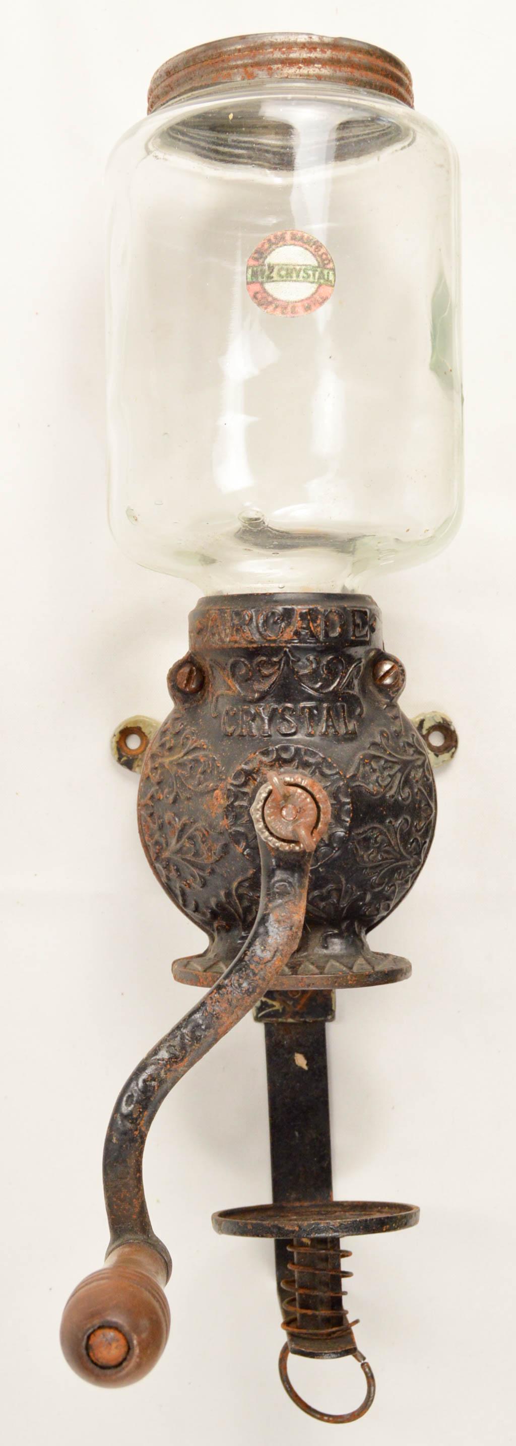 Arcade Crystal No. 2 Wall Coffee Grinder: Wall mount hand crank coffee grinder made by the Arcade Mfg. Co. of Freeport Illinois. Glass hopper has a paper label. This is an Arcade Crystal No. 2. In good condition. Hopper has no chips or cracks
