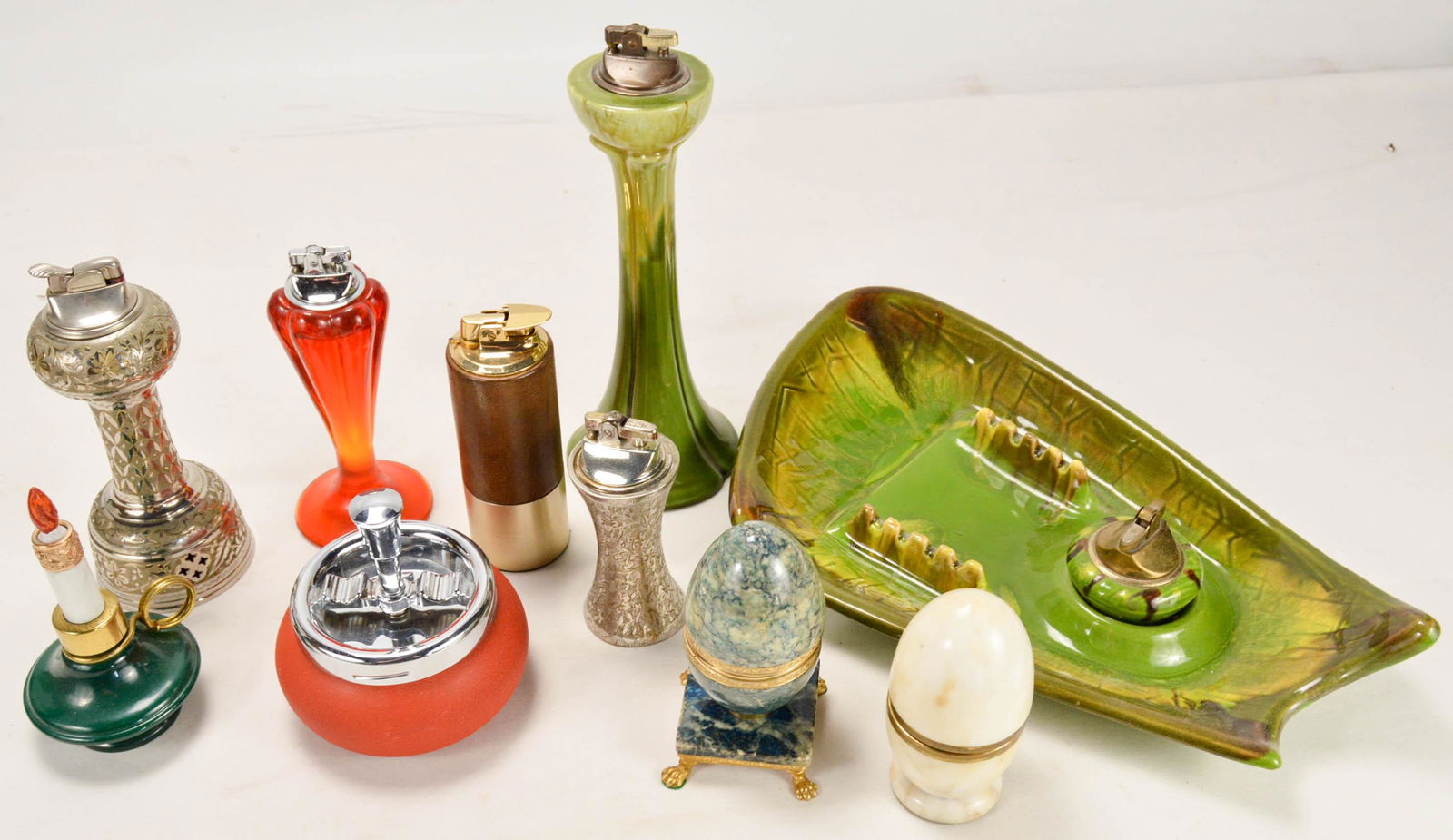 Lot of Large Lighters And Ash Tray: Lot of Large Lighters And Ash Tray. Collection of larger table lighters. Includes wind up musical lighter (tall silver, 7.5" tall). 5.5" tall candlestick. Royal Haegar 10.5" green lighter. 5 other var