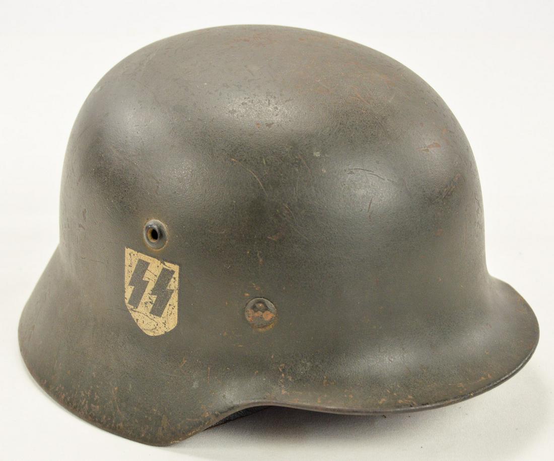 WWII German M35 SS Helmet: A German SS M35 helmet with single SS sig runes decal on right side. Decal has some wear and is around 75% intact. Helmet is complete with liner and chin strap. Helmet's feldgrau paint is worn with so