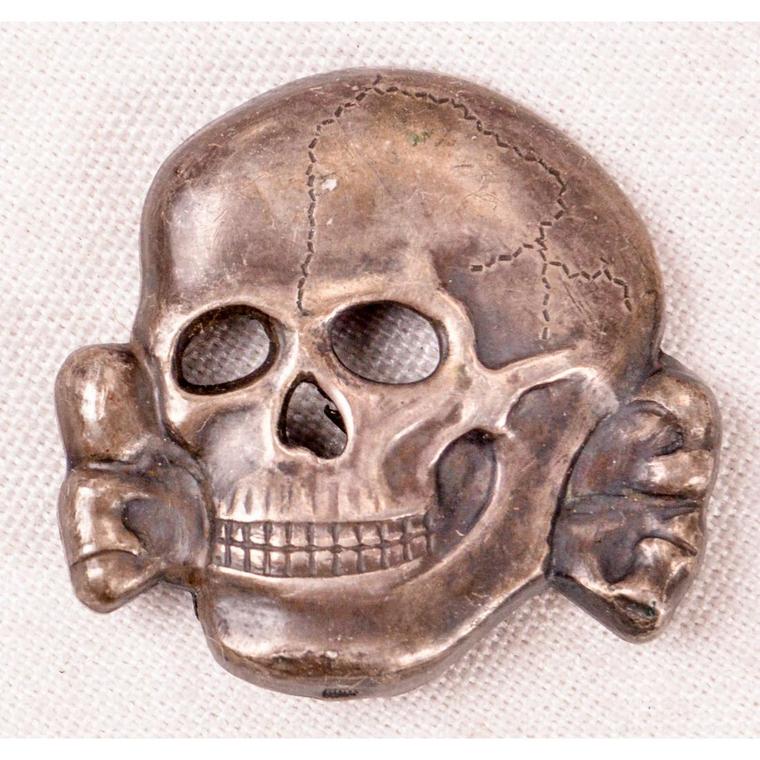 WWII German SS Totenkopf Cap Badge: A cap badge of the infamous German SS Totenkopf (Death's Head), used widely by the SS during WWII. Inside of badge is marked "RZM" above "SS 223/39". Badge is complete with pins on back. Overall very