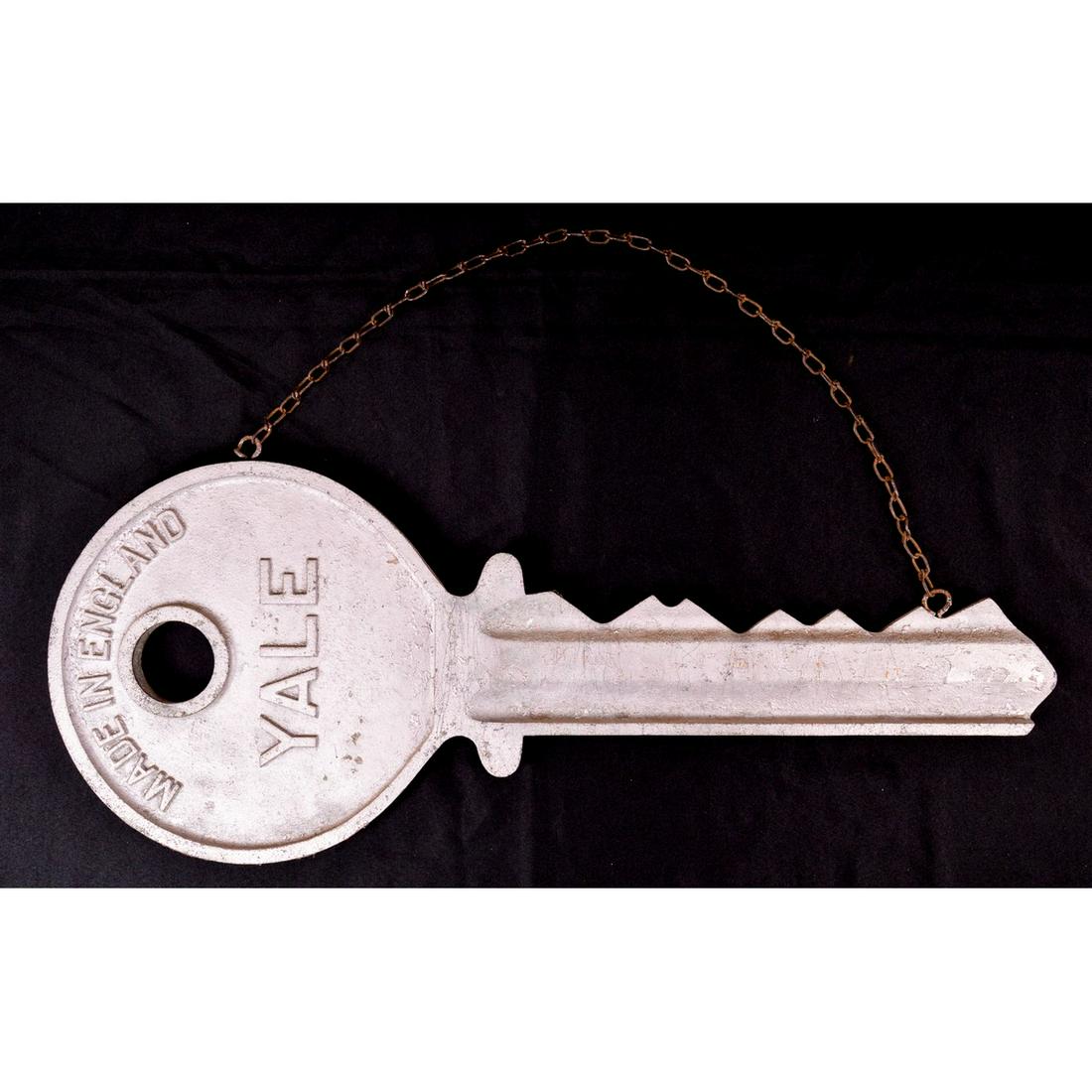 Yale Oversized Key Advertising Sign: A large oversized key sign with the key reading “Yale” and “Made in England”. Key has an attached chain for hanging on wall. Key has some scratches and wear to paint but is in overall good con