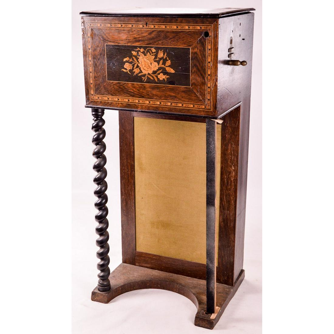 Small Barrel Piano Console: Inlaid wood case with an early barrel piano. Some loose lifting veneer and lay present on cabinet. The parts set appears complete(?) but it needs a total rebuild. Has attractive barley twist front leg