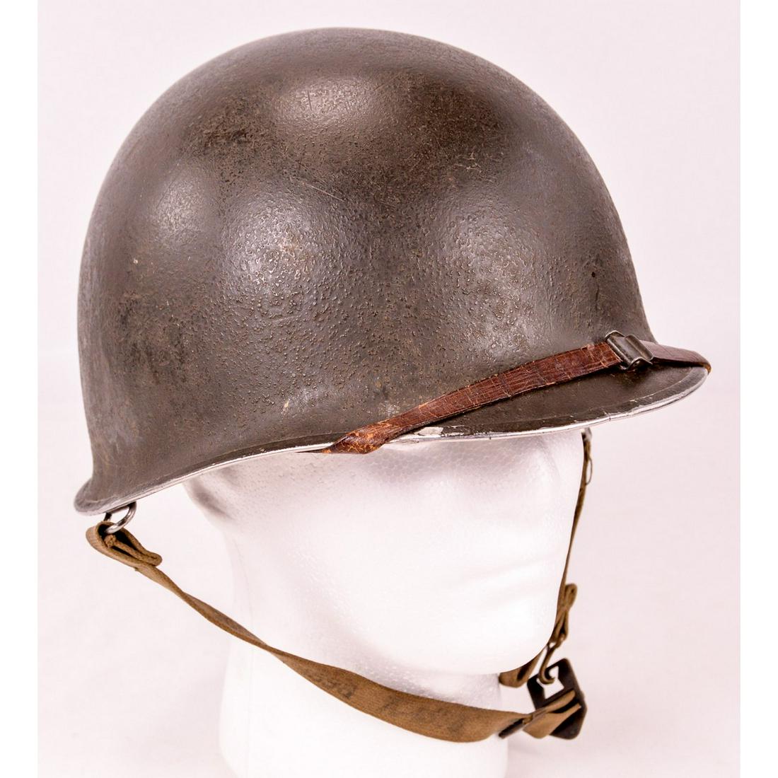 WWII US M1 Helmet & Liner: A WWII era US M1 helmet complete with liner with leather chin strap. Helmet has front seam and swivel bails. Liner is marked with Miner Safety Appliances logo. Helmet shell has dark olive drab paint w