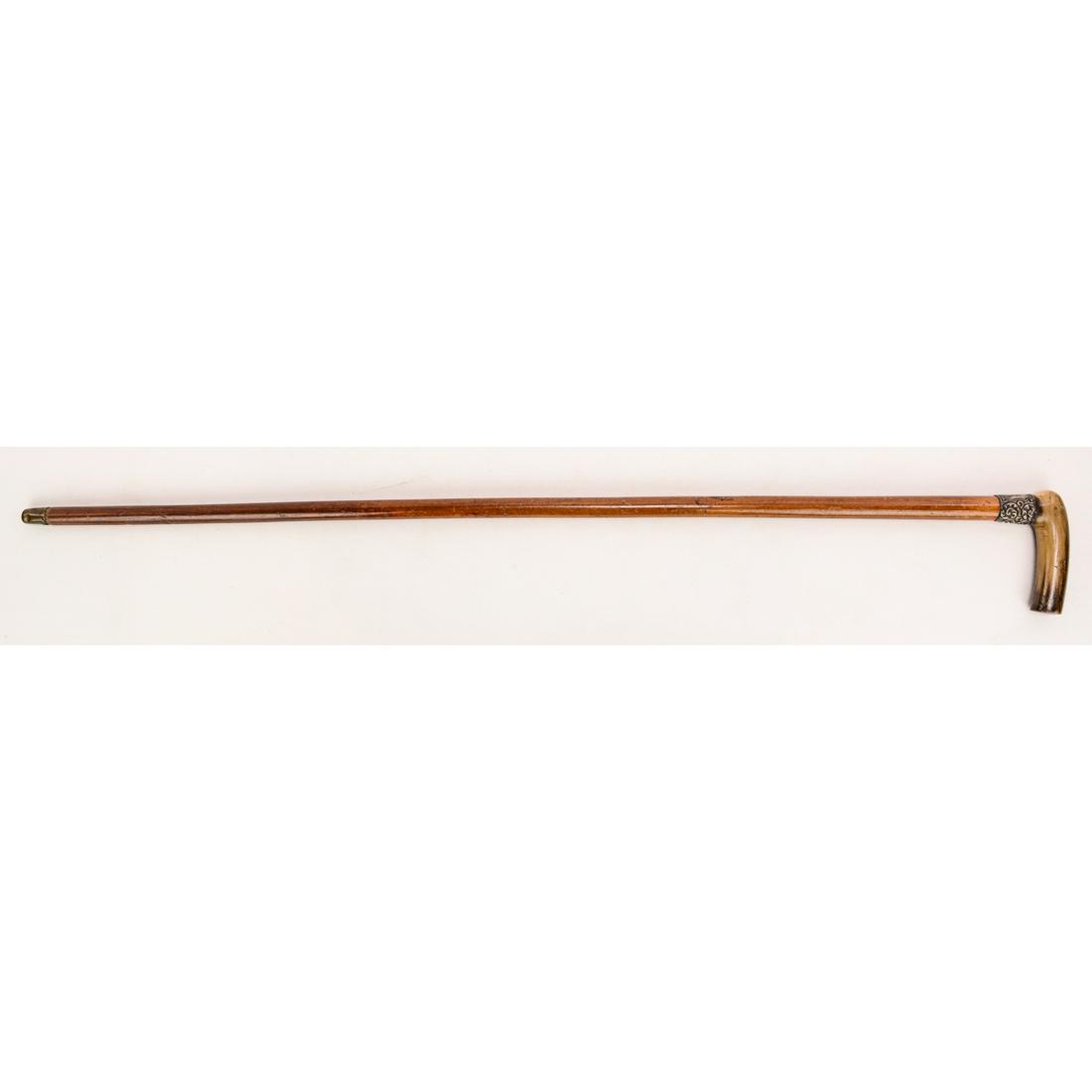 Horn and Sterling Silver Handled Walking Stick: This walking stick features a horn handle and a hallmarked sterling silver mount. The finish on the wood is scratched and scuffed, and the shaft is slightly curved. The tip is horn, to prevent slippin