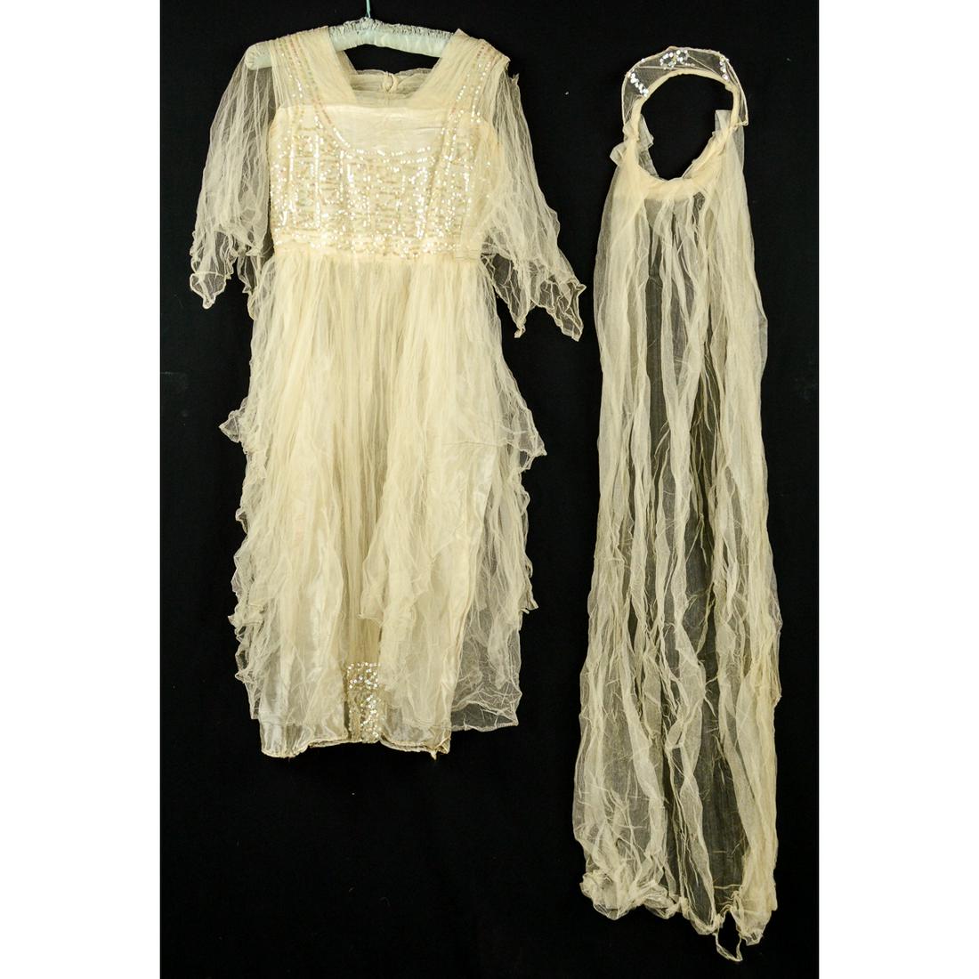 Early 1920s Wedding Gown with Long Veil: Sheer netting covers satin bodice and skirt on this early 1920s wedding gown. Slight underarm stains. Sequins covers top bodice and bottom of front panel. Headpiece has 4 ft long veil and princess cro