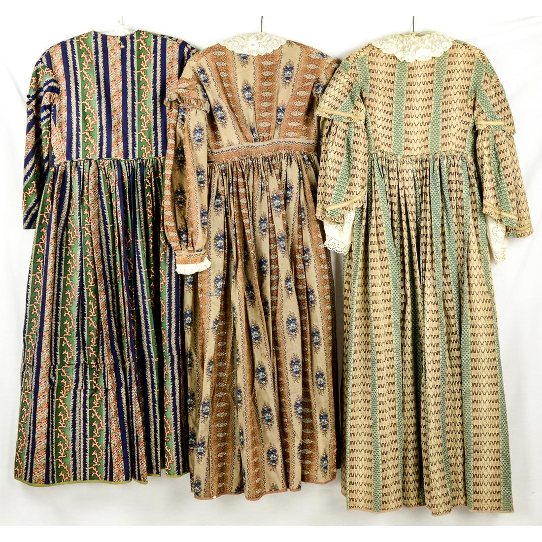 3 1840's-50's Prairie Style Ladies Dresses: Brown/green striped cotton dress, glass buttons up the front, with lace collar and sleeves, slight damage has been repaired on front, waist 26". Brown/tan/blue flowered prairie dress, lace collar and