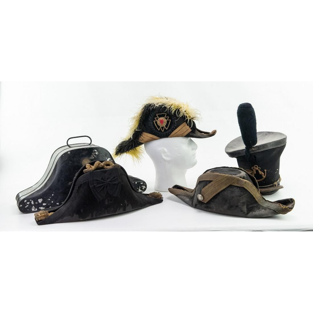 US Navy Bicorn and Shako Hats w Bicorn Hat Box 4Pc: The shako has its badge and plume. It is misshapen and missing its chinstrap. The Navy bicorn case has a Harry H B Badmane manufacturer plate on it. The bicorn hats have some damage. See Photos
