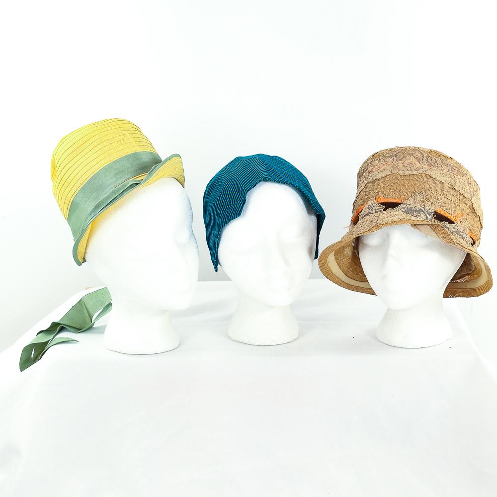 3 1920 Cloche Hats: A bright green, elastic back small cloche. Four-points frame the face - lined in two way silk. Rows of yellow straw make up this deep cloche. Trimmed in Kelly green grosgrain ribbon with a bow and lon