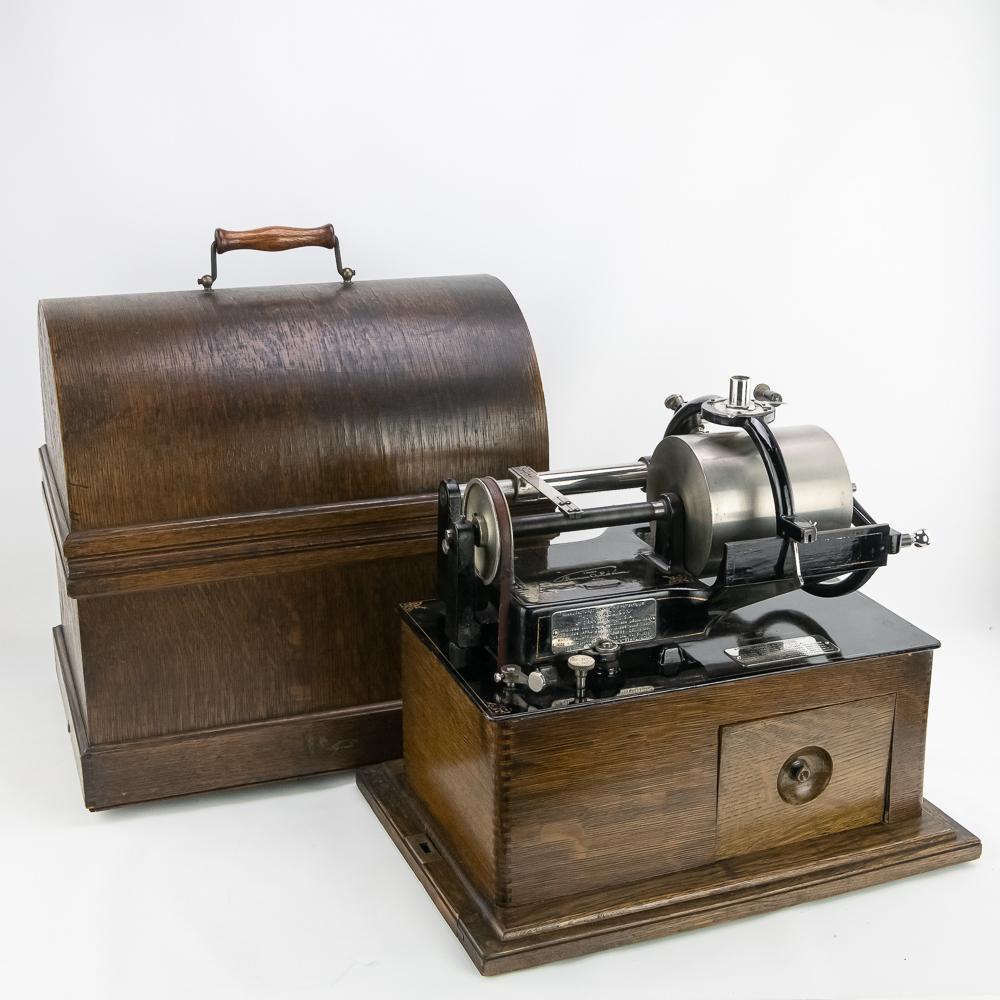 Edison Concert Cylinder Phonograph: This machine in its first style oak cabinet with its large enveloping cover has its original finish on both the cabinet and cover in good original condition. There is some minor staining and discolora