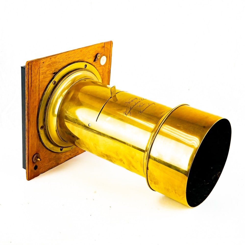 Large Brass Lens by Voigtlander & Son: Vienna and Braunschweig, No. 19529, with single Waterhouse stop, mounted on an oak lensboard,/pneumatic shutter, the lens 11 3/4"L., element diam. 4".