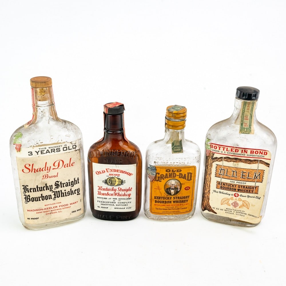 Four Vintage Whiskey Bottles With Labels: Two 1/2 pint and two 1 pint vintage whiskey bottles with front and back labels. Brands include Old Underoof, Old Grand-Dad, Shady Dale and Old Elm. All four are in good original condition with federal