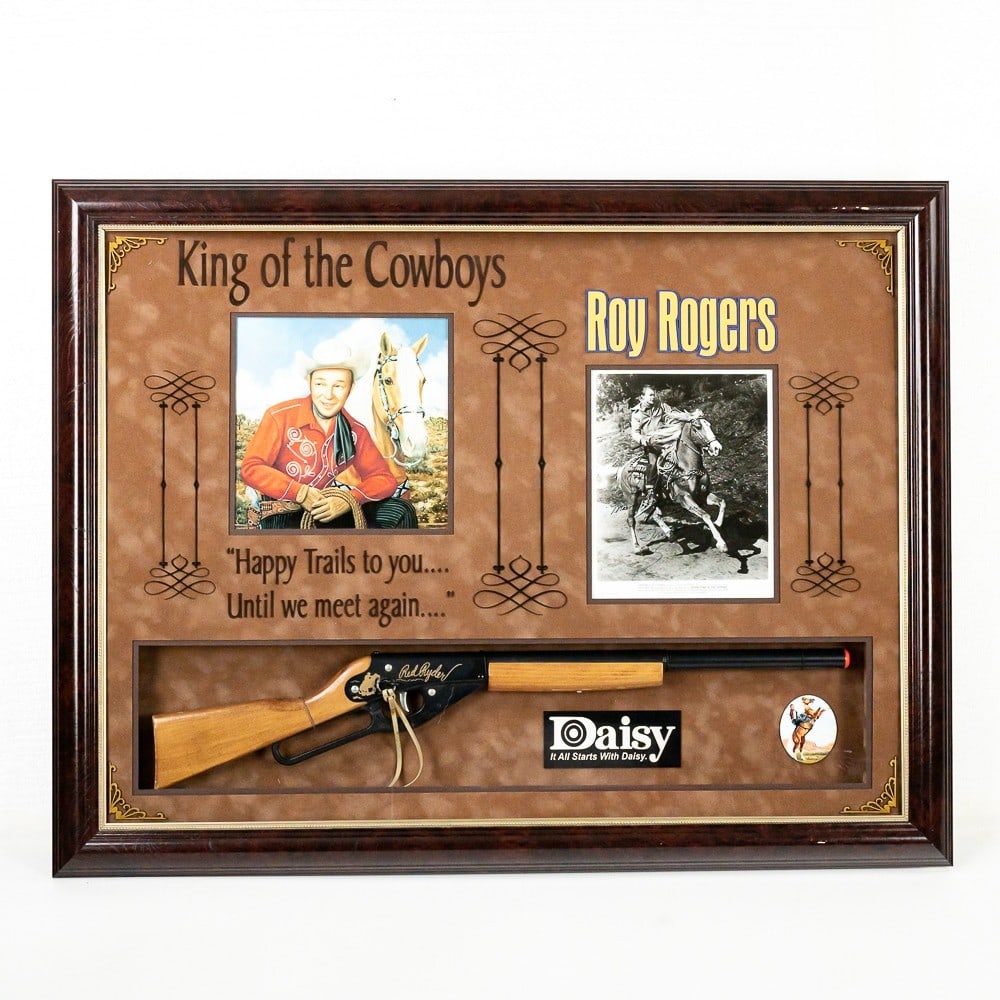 Roy Rogers King of the Cowboys Signed Photo: Promotional photograph signed "To George Braden Many Happy Trails Roy Rogers & Trigger." A Daisy Red Ryder BB Gun and a COA issued by Authentic Autographs Unlimited are included. 38 1/2" X 29 1/2" X 3