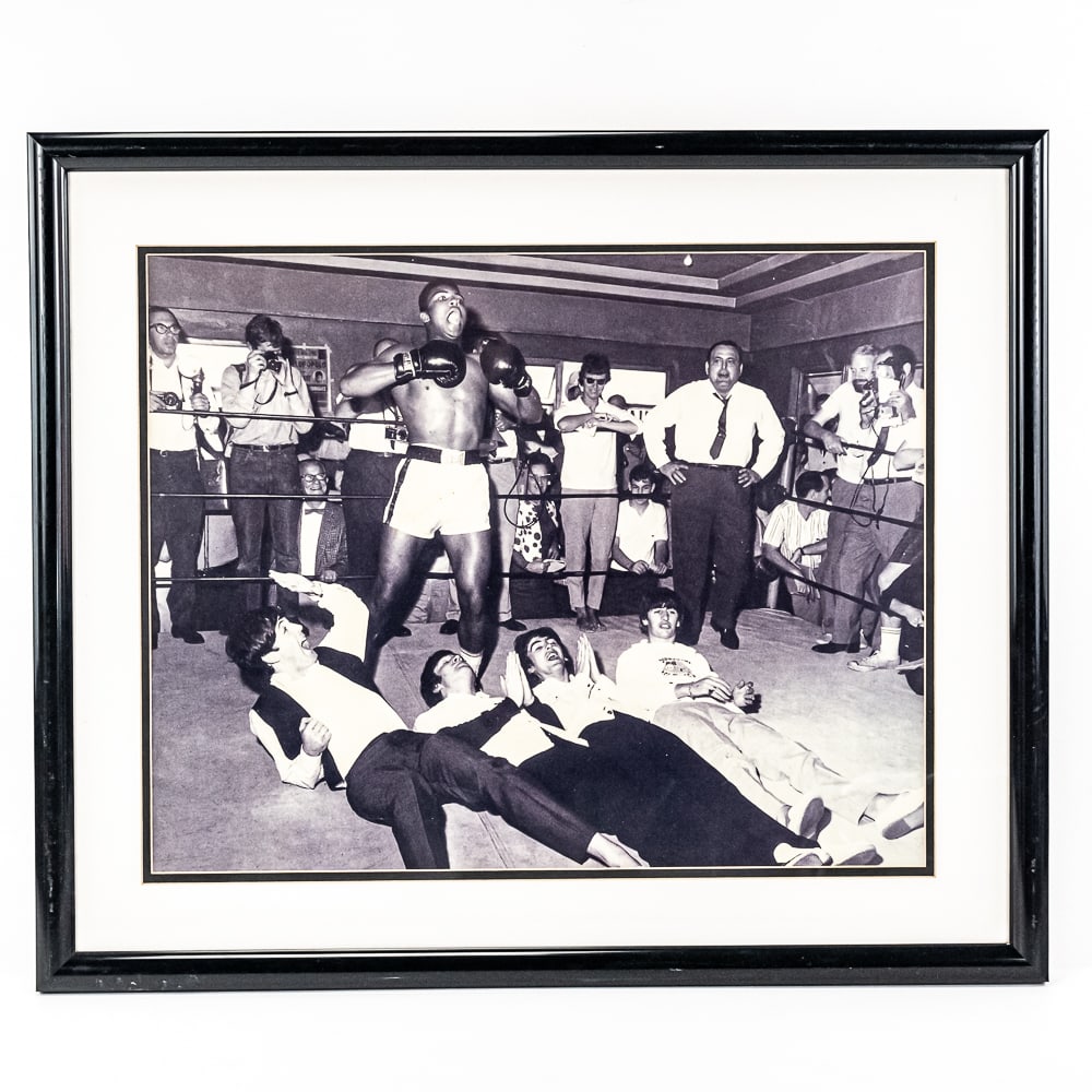 Framed Muhammad Ali Standing Over Beatles Photo: Professionally framed and matted vintage 16"t x 19'w photo of Muhammad Ali Standing Over The Beatles. Approximately 21.5"t x 25.5"l in good overall condition with minor surface scuffs on the frame. Pe