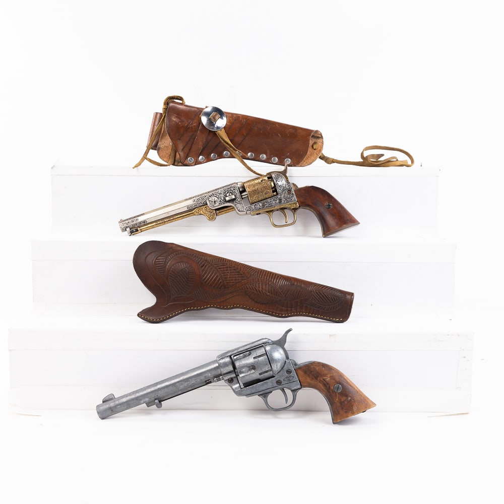 2 Denix Replica Colt Revolvers: 2 Denix Made Replica Colt SAA and percussion revolvers. Cast metal non-firing replica weapons are 7.5" barreled with wood grips and one brasss colored frame. Both guns come with high quality leather w