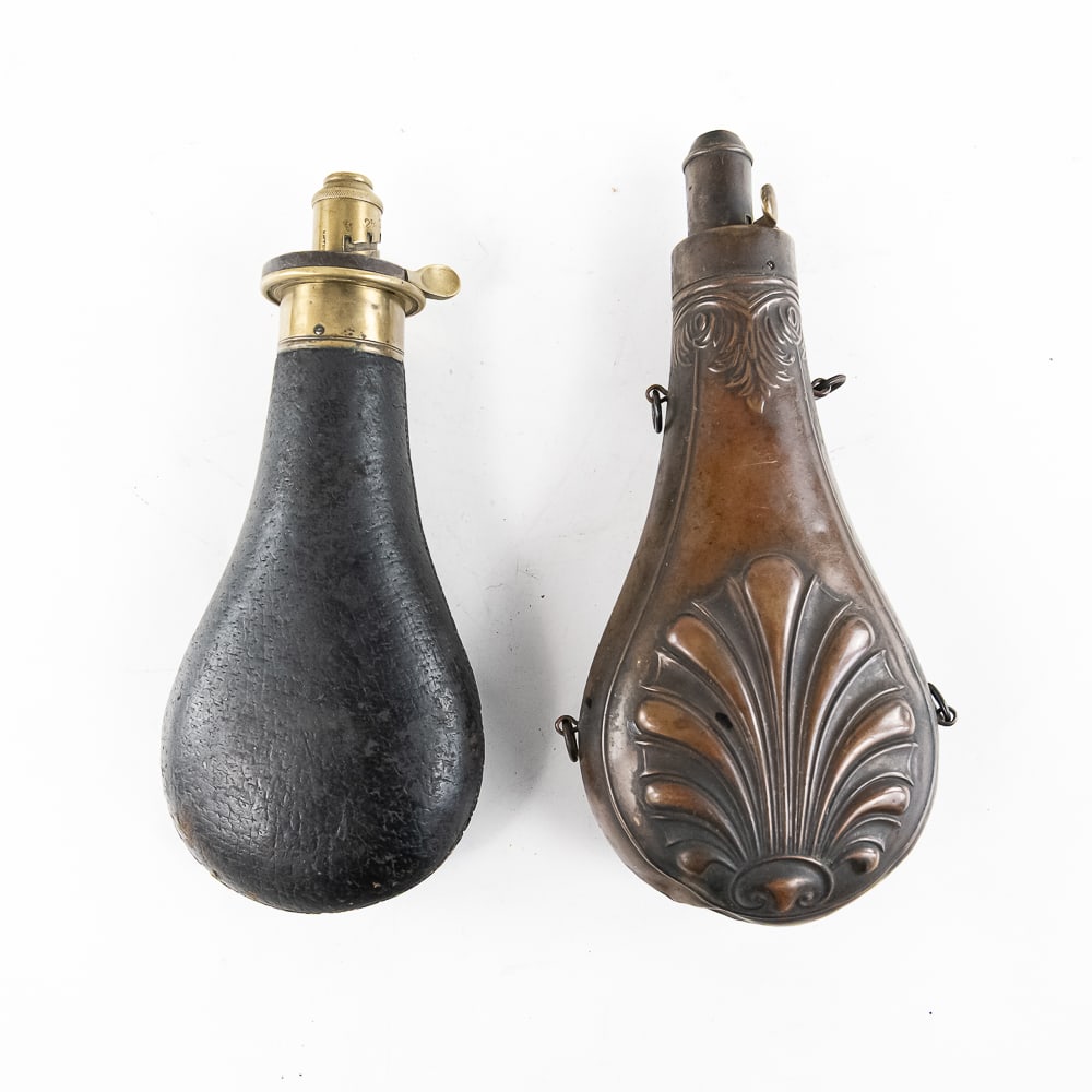 Pair of Antique Black Powder Flasks: Pair of black powder flasks circa late 1800s early 1900's. 1) The first powder flask is copper/brass and has a floral/shell motif throughout. There are a few dents at its base, but overall it is in fa