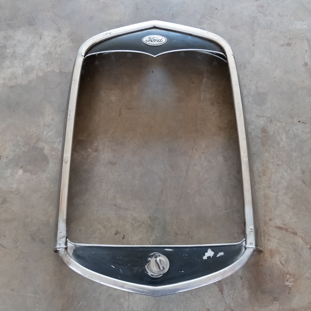 1931 Ford Model A Radiator Shell: Original,. used stainless steel shell with Ford emblem and crank hole cover with some damage. See pics.