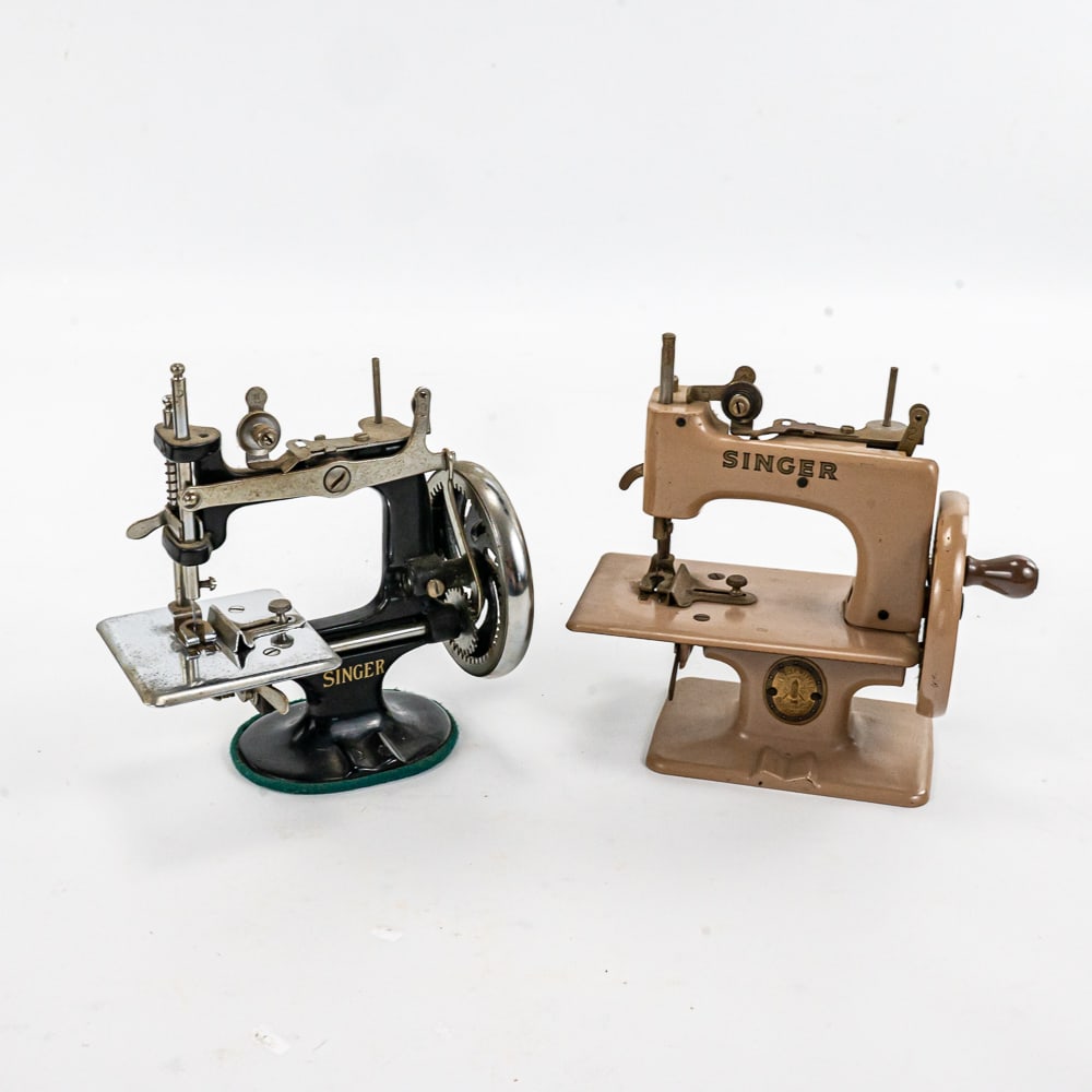 Singer Sewhandy Model 20 & K-20 Sewing Machines: 1950s Singer Sewhandy model 20 & contemporary Singer K-20 cast metal bodied hand operated sewing machines. Each stands approximately 7" tall. Both are in good to very good overall condition with some