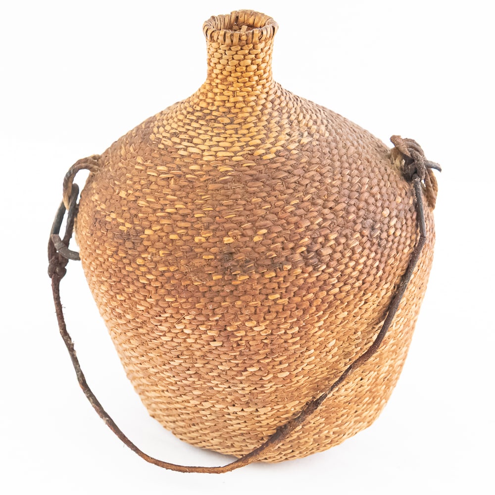 1970s Twined Paiute Water Vessel: Paiute water vessel circa 1970s. Known as a tus this tightly woven basket made from plant fibers and was traditionally used by Paiute people for carrying water. It looks to have resin between the fibe