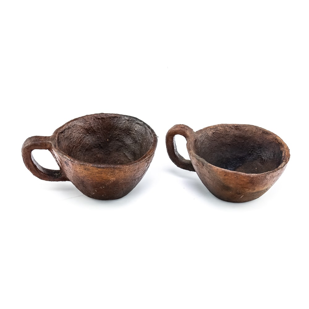 Pair of Apache Clay Cups: This pair of Apache clay cups are handmade with a rustic aesthetic mimicking western commercially manufactured coffee cups. Manufacture date unknown. Their exterior is rough and they look to be covere