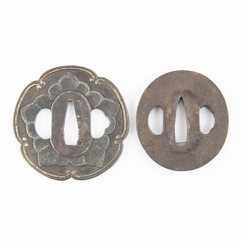 Antique Japanese Iron Tsuba Sword Guards (2)32wwww: This pair of Japanese tsuba (sword guards) represents distinct styles of Edo-period metalwork, likely crafted for a katana or wakizashi. The first is a robust maru-gata (round) iron guard featuring a