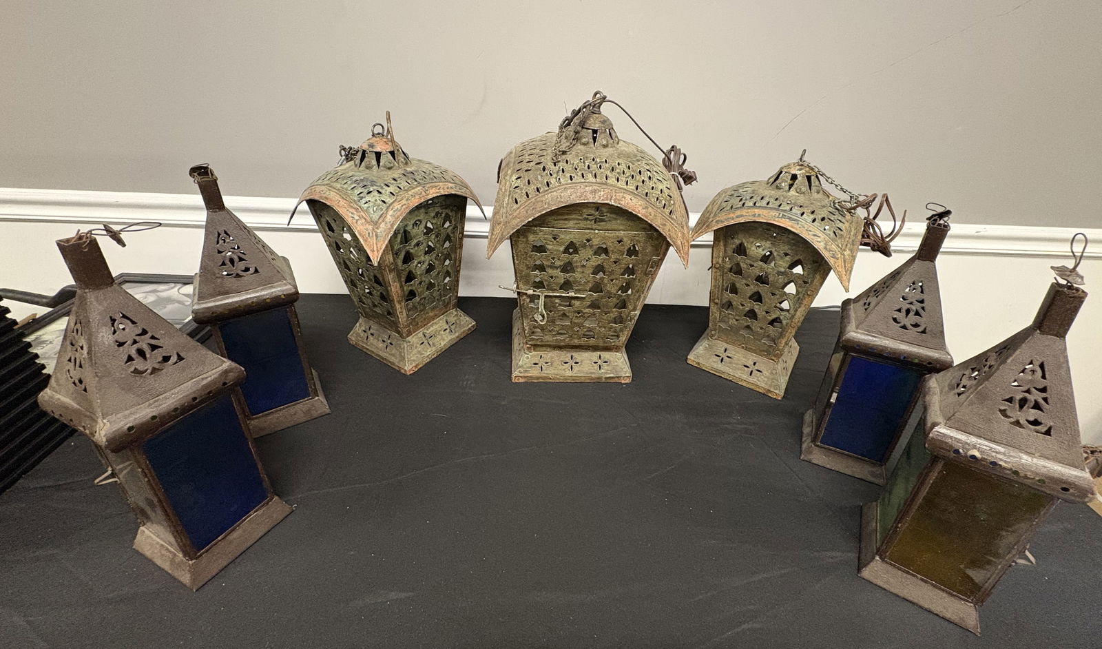 Seven Ornate Moroccan Style Lantern Collection (7): This impressive seven-piece assembly features a curated mix of Moorish and North African-inspired lighting. The trio of larger electrified lanterns showcases a heavy verdigris patina over what appears