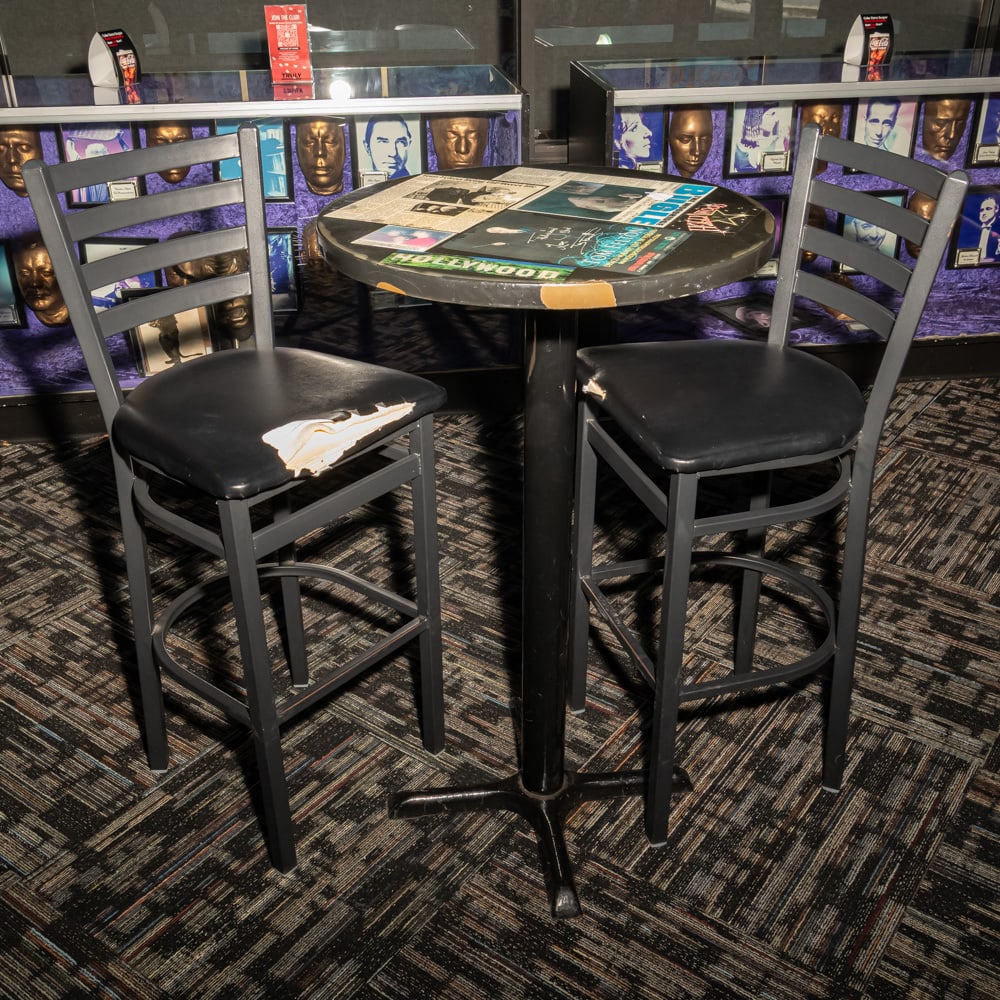 Tom Felton Auto Harry Potter Cafe Table w/2 Chairs: Expelliarmus! This unique pub-style bistro set features a round wooden pedestal table and two metal bar-height chairs, heavily themed with Tom Felton (Draco Malfoy) memorabilia. The tabletop serves as