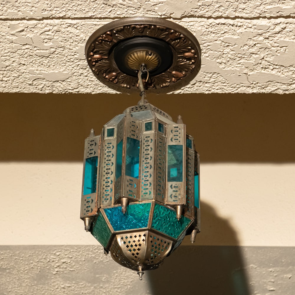 Vintage Moroccan Style Stain Glass Chandelier Exit: Moroccan-inspired hanging chandelier captures the essence of Moorish design with its intricate pierced metalwork and vibrant stained glass panels in shades of emerald green and turquoise blue. The