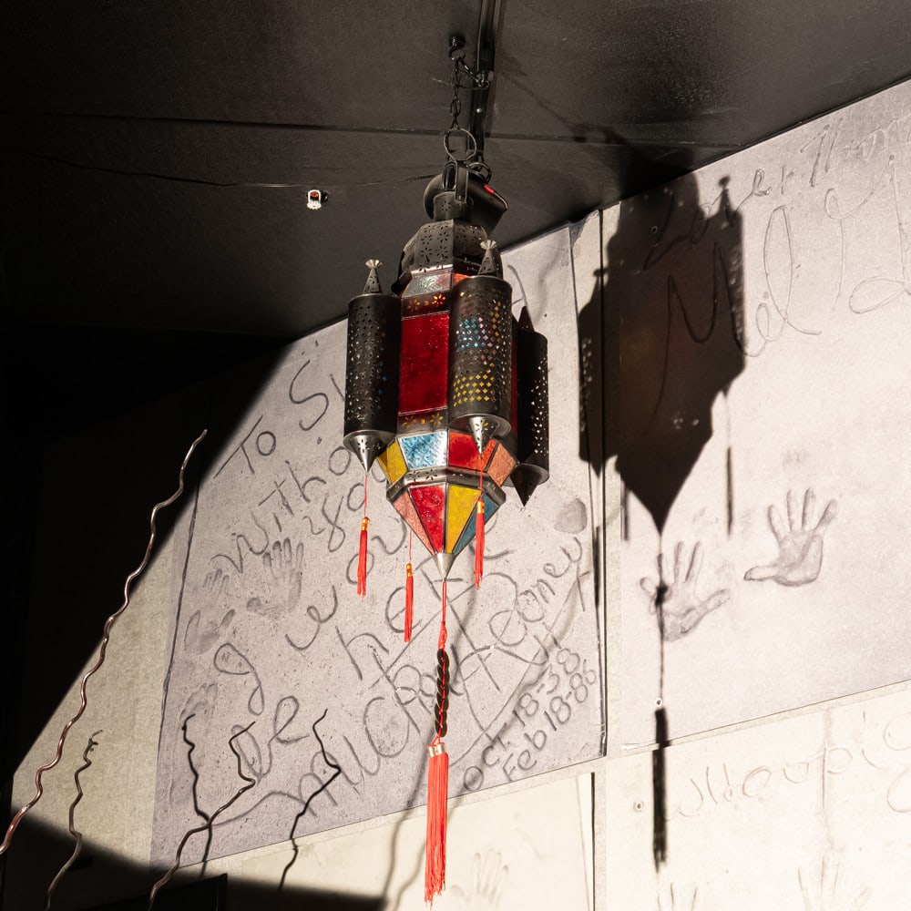 Ornate Moorish Style Stained Glass Chandelier: A striking example of a Moorish or Moroccan-style hanging lantern, featuring a central hexagonal body with vibrant red, amber, and blue slag glass panels. The fixture is flanked by four cylindrical, p