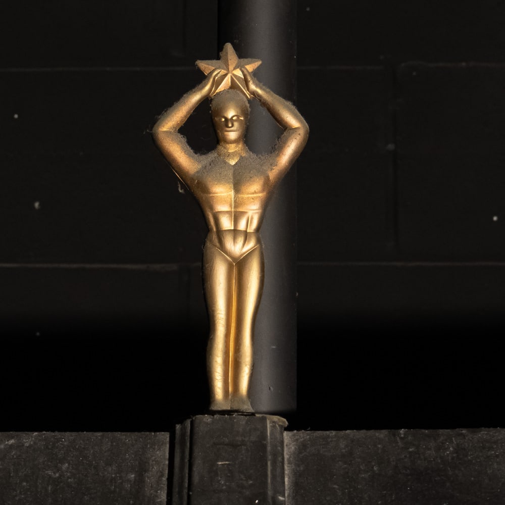 Movie Star Award Statue: Gold metal statue of a stylized Art Deco man holding a star above his head. Mounted on a 4" X 4" X 1" stone base. Measures 10" tall. Please use photos to judge condition and bid accordingly. Please no