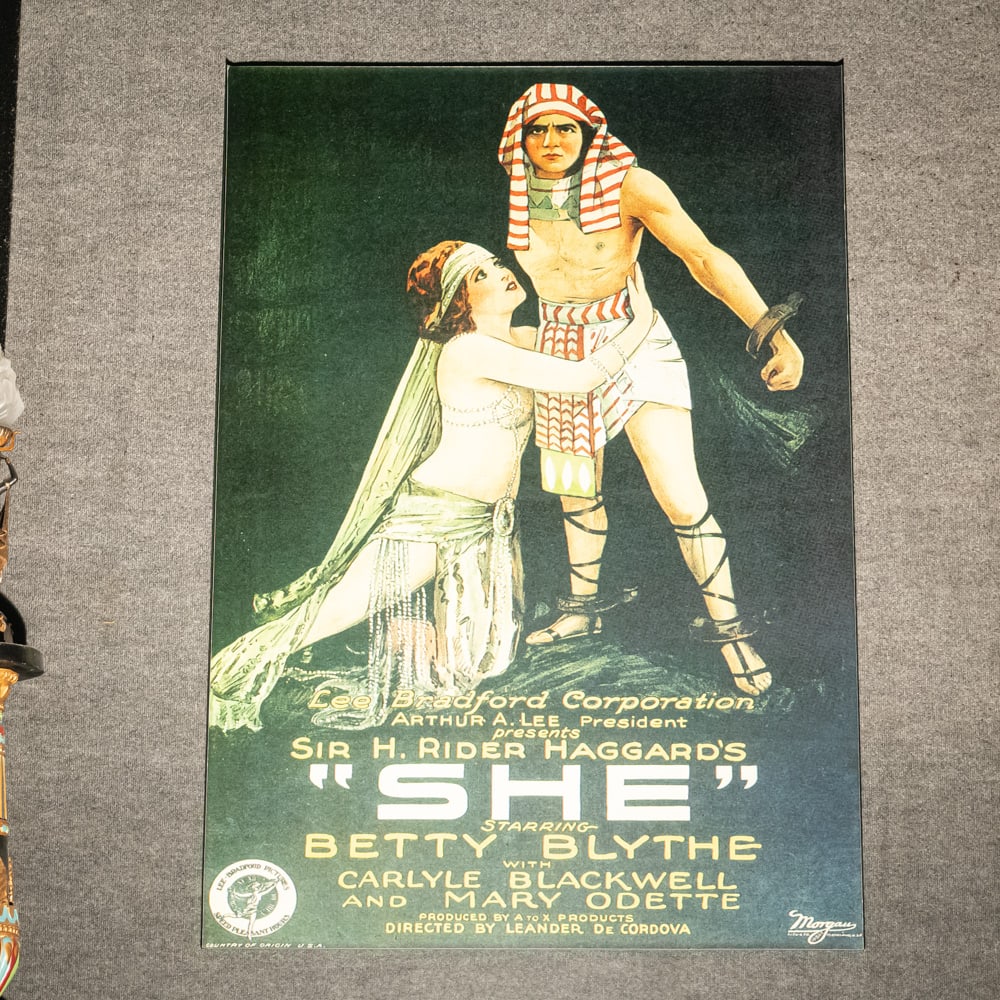 1925 "She" Contemporary Movie Poster: This striking contemporary portrayal of the classic 1925 "SHE" movie poster, starring the legendary Betty Blythe, serves as a bold and cinematic centerpiece for any sophisticated home or office. The p