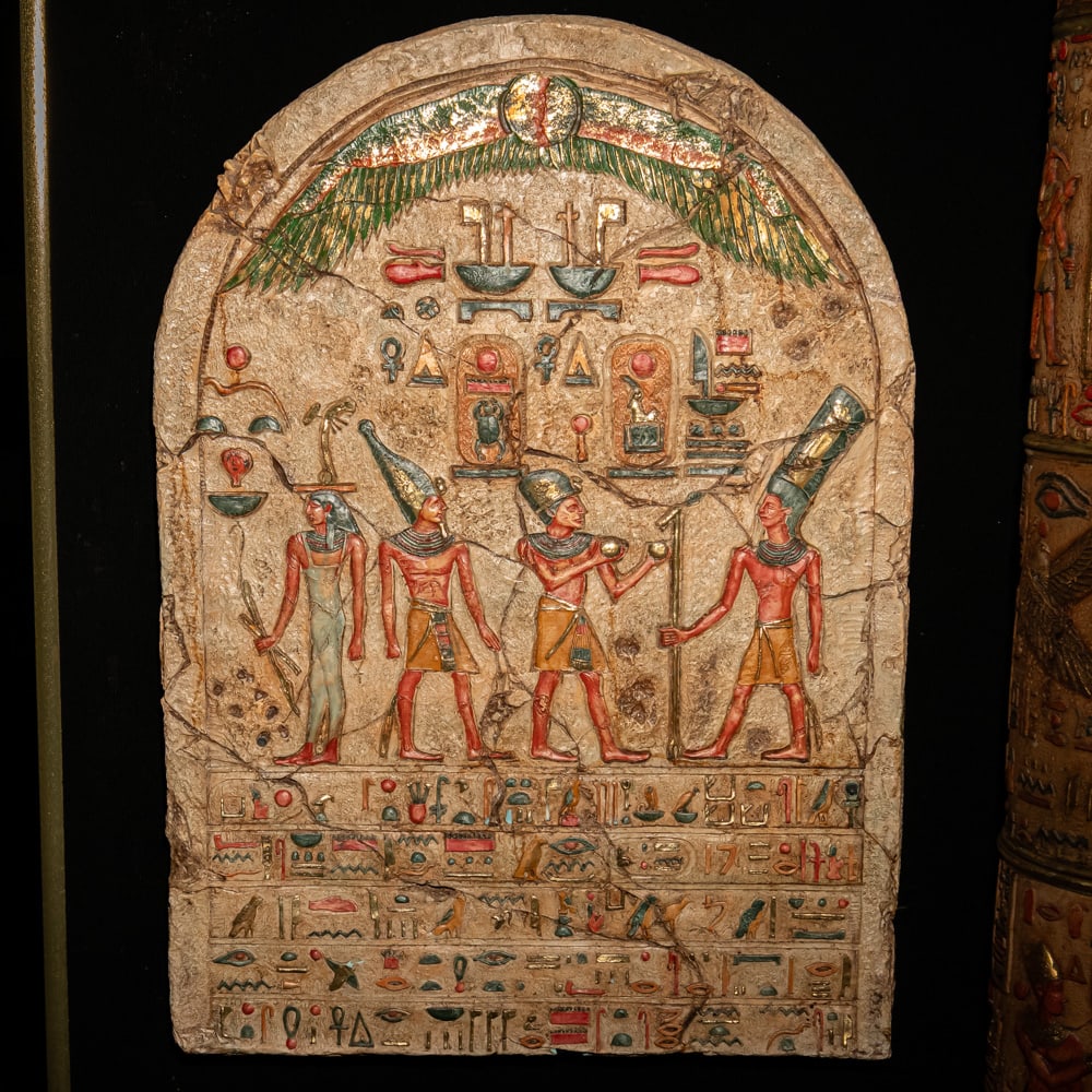 Egyptian Revival Polychrome Resin Stele: This grand-scale Egyptian Revival wall relief is expertly cast in resin to emulate the appearance of ancient weathered limestone. The piece captures the iconic New Kingdom aesthetic, featuring a