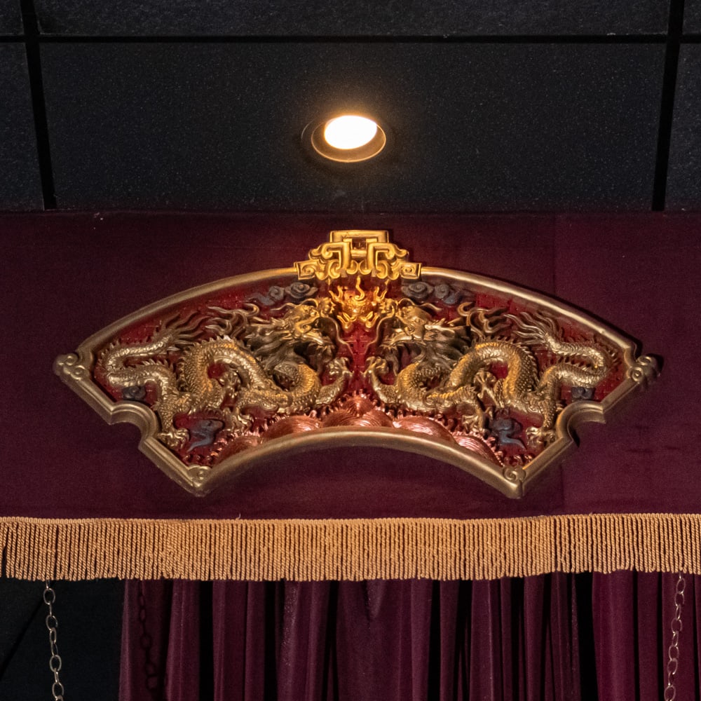 Ornate Gilded Dragon Fan Wall Decor (R): This striking piece of Chinoiserie features a relief-carved fan-shaped panel depicting two imperial dragons chasing a flaming pearl, a classic motif symbolizing power and good fortune. The intricate c