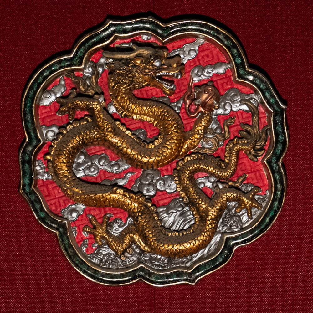 Opulent Gilded Chinese Dragon Decorative Plaque: Exquisite decorative plaque showcasing a high relief coiled Chinese dragon perfectly accented with a scalloped boarder. Presents well with vibrant red background enhancing its opulent metallic contras