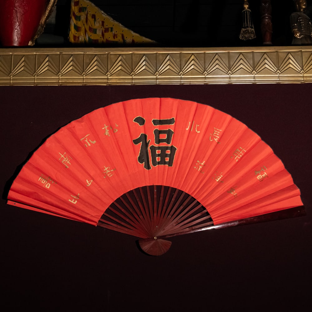 Large Vintage Red Chinese "Fu" Wall Fan (R): This is an impressive, oversized decorative folding wall fan featuring a vibrant red paper or fabric leaf. The central focal point is a large, hand-painted black calligraphy character for "Fu" represe