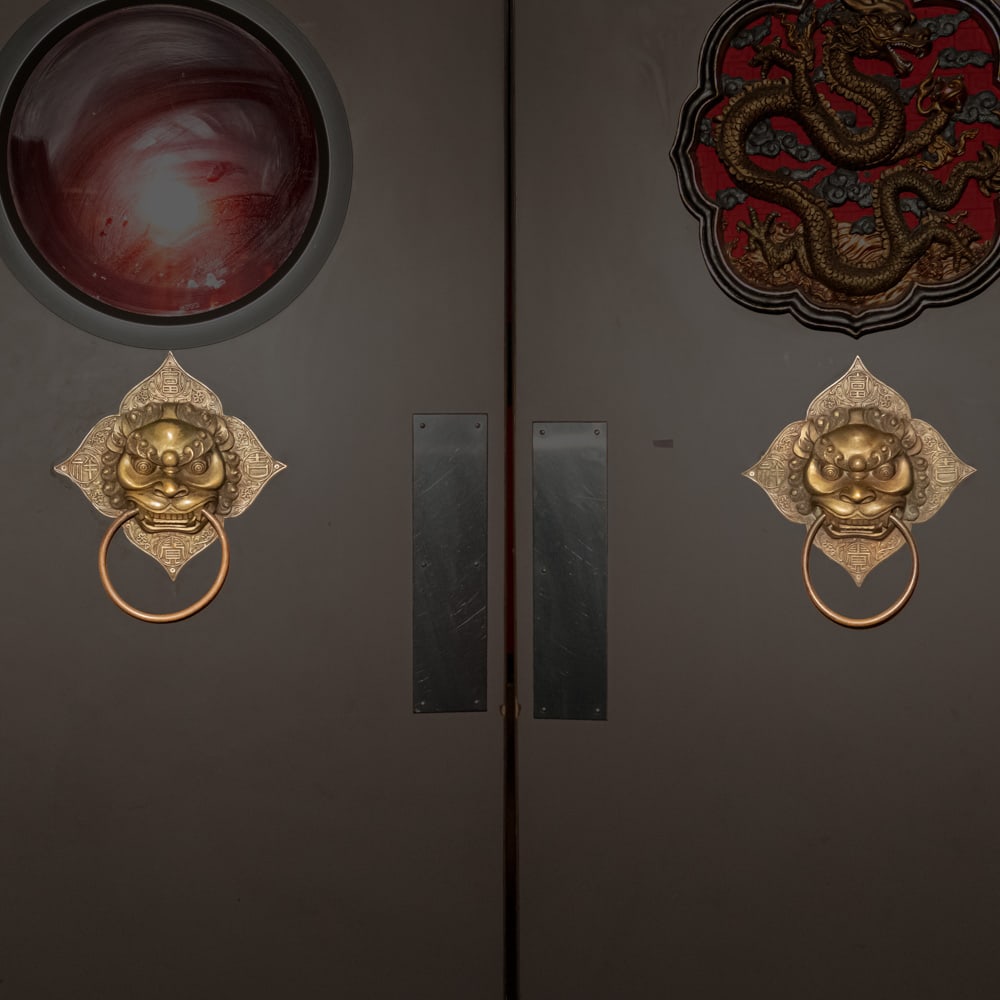 Pair Chinese Brass Guardian Lion Door Knockers: This impressive piece is a classic Chinese "Shishi" (Guardian Lion) or "Taotie" door knocker, cast in heavy brass with a rich, aged patina. The central mask features the fierce, bulging eyes and styli