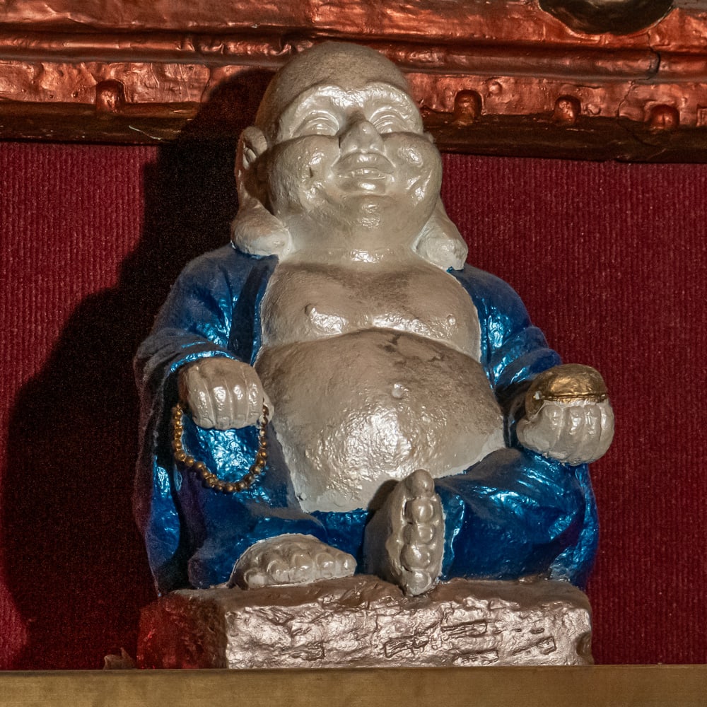 Painted Ceramic Laughing Buddha Statue: This charming "Budai" or Laughing Buddha figure, captured in a seated position, reflects a popular mid-20th-century folk-art style likely of Chinese or East Asian origin. The piece is crafted from hea