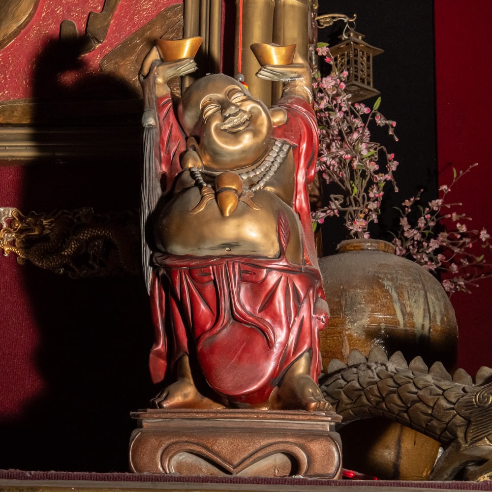 Vintage Chinese Carved Laughing Buddha: A delightful representation of Budai, the Laughing Buddha, depicted in a classic "Double Wealth" pose holding two gold ingots (yuanbao) aloft. This piece features a rich, hand-painted polychrome finis